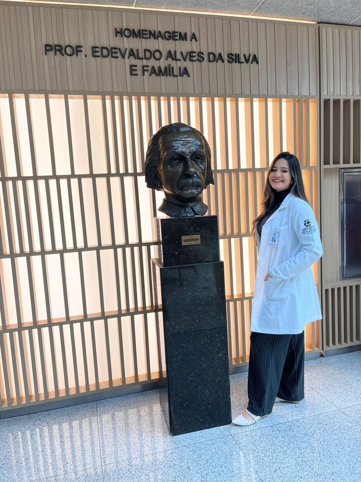 Dra. Échilen Rodrigues sorrindo no seu consultório, em um ambiente de terapia.